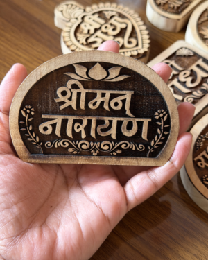 Close-up of a hand holding a round wooden plaque with carved script and decorative border; other plaques visible in background.
