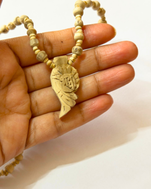 Wooden beaded necklace held between fingers with a carved pendant visible on the cord.